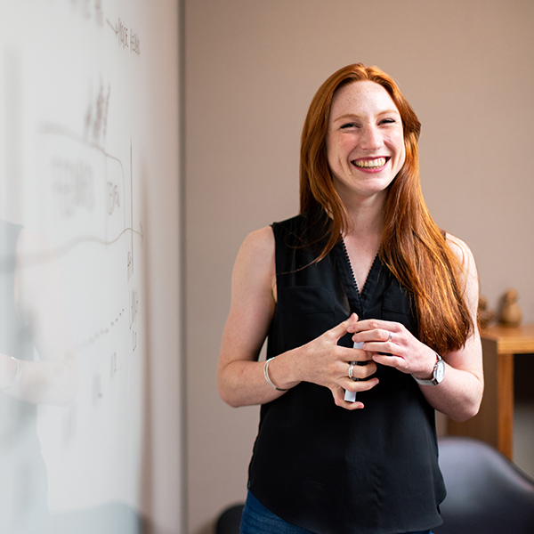 woman at a whiteboard smiling